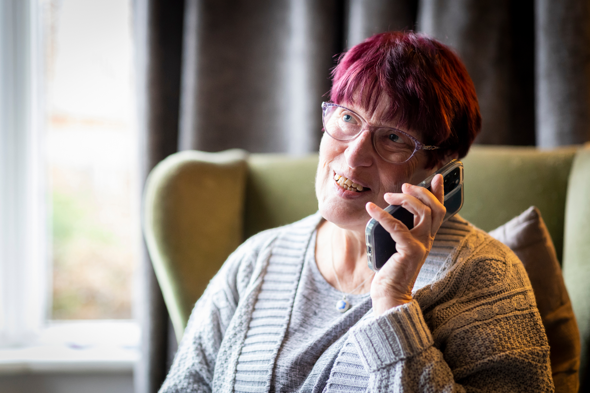 An older adult reading messages on a phone from an online romance scammer.