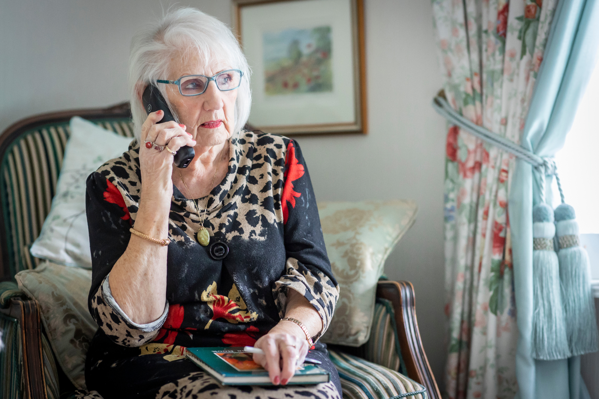 A worried grandmother on the phone during a suspected grandparent scam call.